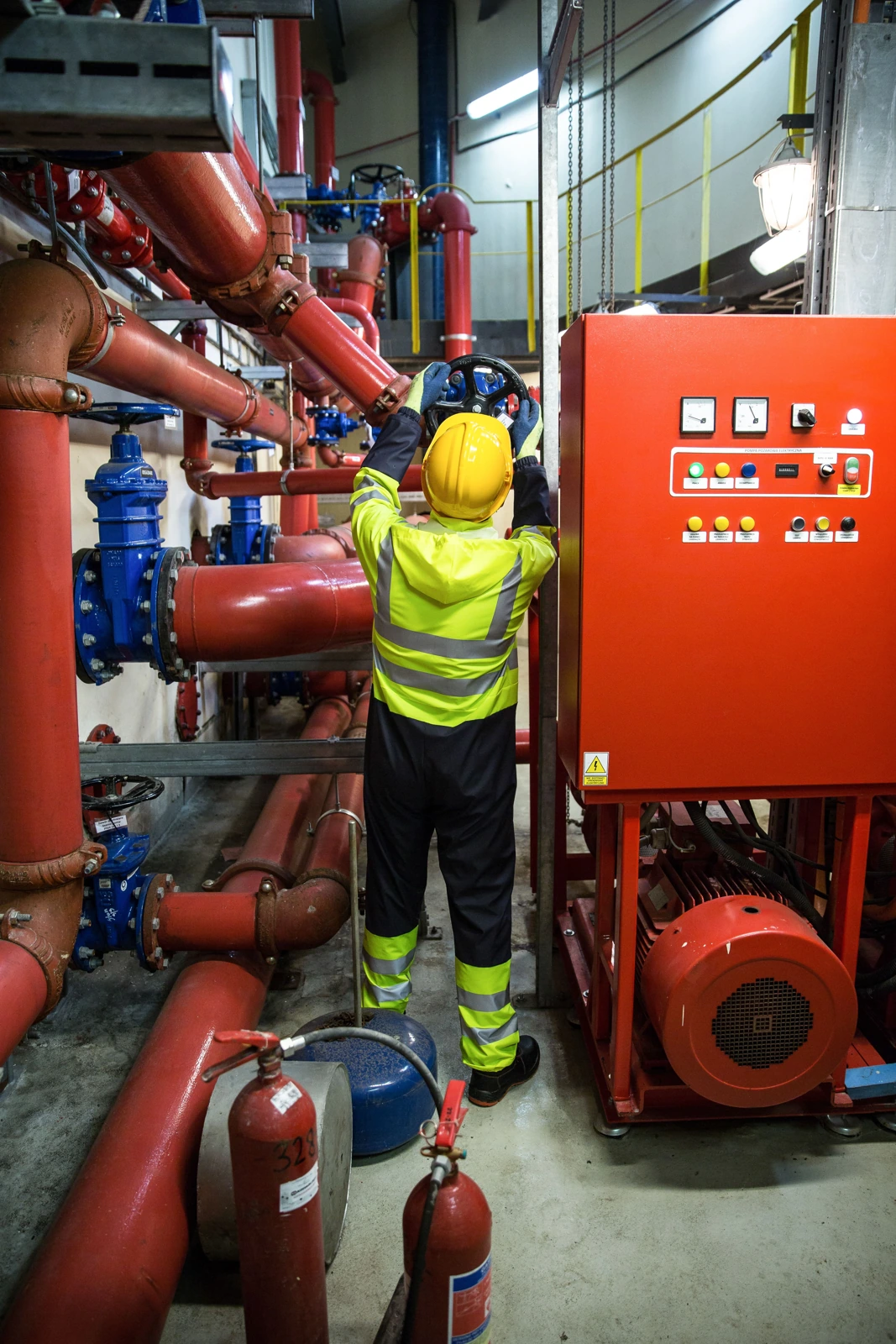Specialist technician inspecting a fire protection valve beside the pump control panel